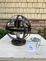 Side view of bronze spherical flush mount fixture with bulbs installed and mounting plate visible