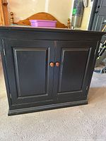 Front view of black wooden cabinet with two doors and round knobs