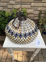 Full view of stained glass pendant light on table showing overall shape and chain