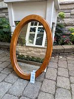 Front angled view of oval pine mirror leaned against table