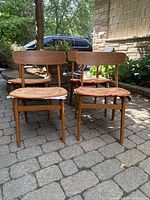 Front view of four teak chairs showing frames and missing seats