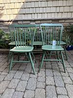 Front view of five green spindle-back chairs arranged outdoors