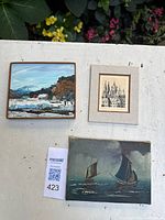 Group shot of three artworks: framed landscape, matted architectural drawing, marine painting