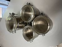 Top view of all four chrome canisters showing lid style and size differences