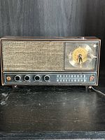 Front view showing speaker grille, clock dial, control knobs and tuning scale