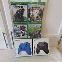 Group shot of two sealed controllers and four sealed games