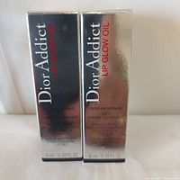 Front view of both Dior Addict Lip Glow Oil boxes showing product name and volume