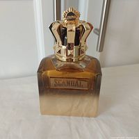 Front view of Jean Paul Gaultier Scandal Absolu Pour Homme Parfum bottle showing gold crown cap and gradient glass