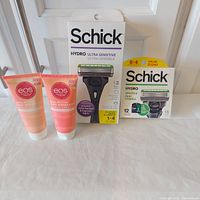 Front view of all four retail-sealed items: Schick razor kit, Schick 12-cartridge pack, two EOS shave cream tubes