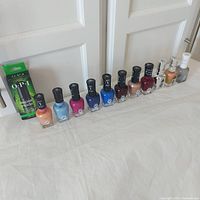 Full lineup of 12 nail care bottles standing in a row