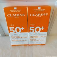 Front view of two Clarins SPF 50+ sunscreen boxes