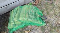 Full green mesh bag of kiln dried split firewood under structure