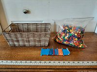 Basket, sealed bag of assorted beads and elastic cords displayed with ruler for scale