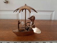 Front view of brass duck rowing boat with frog under umbrella showing overall design