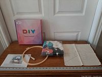 Full kit laid out with box, hoop, yarn pack, canvas, instructions, ruler for scale