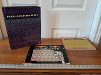 Front view of Holusion Art box, Looney Tunes Magic Eye book, Eye Illusions book with ruler for scale