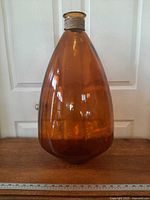 Full view of amber glass floor vase on table with ruler for scale
