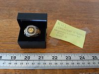Ring in open presentation box beside ruler and note