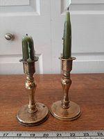 Two brass candlesticks with green candles