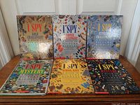 Group shot showing all six I Spy hardcover books upright on table