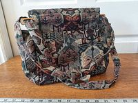 Front view of tapestry purse showing flap, strap, size reference ruler