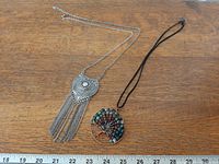 Both necklaces laid flat with ruler for scale