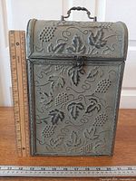 Front view of embossed metal wine trunk with ruler for scale