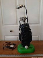 Full view of golf bag lamp on green base with power cord