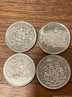 Reverse side of four Canadian 50-cent pieces showing coat of arms and partial dates