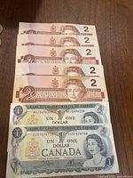 Fronts of six $2 and two $1 notes stacked