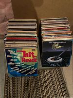 Two tall stacks of vinyl LPs, front sleeves of top records visible