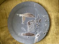 Full view of grey-brown glazed ceramic plate with abstract carved design