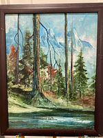 Full view of framed oil painting showing forest, mountains and stream