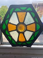 Full view of hexagonal stained glass panel backlit at window