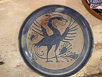 Front view of signed glazed pottery plate with stylized bird design