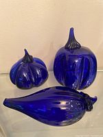 Three cobalt blue blown glass vegetable figures displayed together
