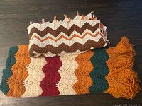 Both crochet afghans folded showing colors and patterns