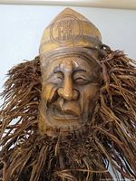 Front view of bamboo root mask with beard and carved facial features