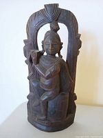 Front view of carved wooden deity statue showing overall design and condition
