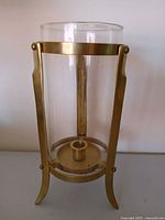 Full view of brass hurricane candle holder showing frame, glass chimney, candle socket