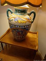 Full view of lamp on table showing shade and majolica base