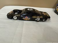 Left side view of die-cast drag car showing decals and slick tires