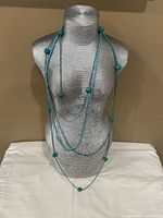 All four blue beaded necklaces layered on mannequin