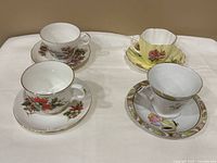 Four bone china cup and saucer sets displayed on table