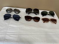 Six pairs of sunglasses laid out in two rows on table