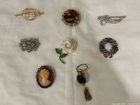All eight brooches arranged on cloth background