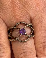 Close-up of ring on finger showing amethyst, diamond accents and band design