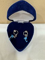 pair of silver stud earrings with blue dolphin dangles in blue velvet heart box