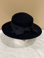 Side view of black felt hat showing ribbon bow and brim