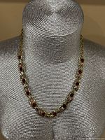 Necklace displayed on mannequin showing stone arrangement and gold-tone setting